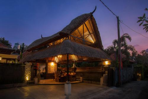a building with a straw roof with a restaurant at Baruna Sari Villa in Ubud