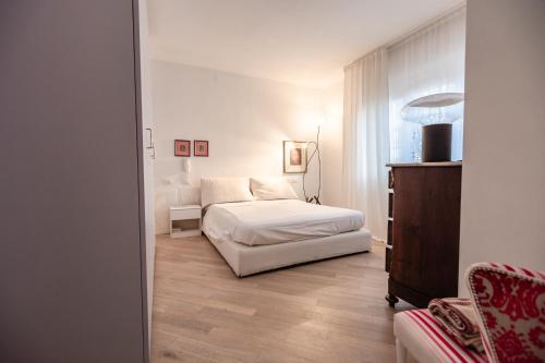 a white bedroom with a bed and a chair at Casa Summer in Cecina