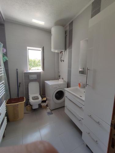 a white bathroom with a toilet and a sink at Villa Hana in Doglodi