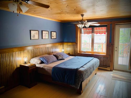 um quarto com uma cama com paredes azuis e um tecto em Chalet & Gîte Capitainerie du Passant em Grandes-Piles