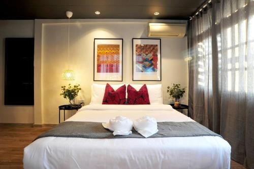 a bedroom with a large white bed with red pillows at Kratib House @ MRT Queen Sirikit 400m in Bangkok