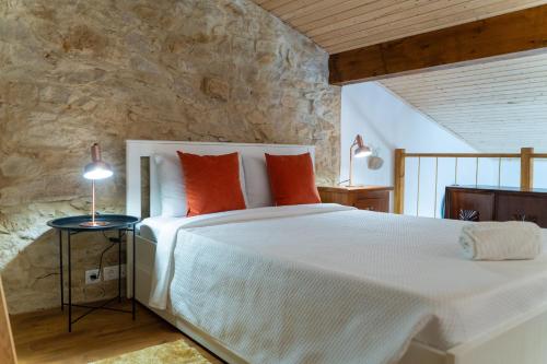 um quarto com uma grande cama branca com almofadas laranja em Casa São José em Carvalhal
