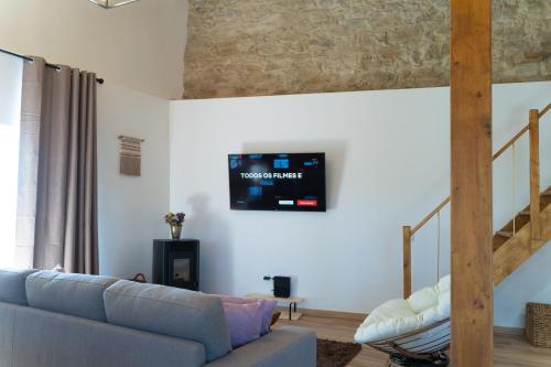a living room with a couch and a tv on the wall at Casa São José in Carvalhal