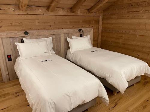 two beds in a room with wooden walls at Chalets Coeur du Lac in Malbuisson