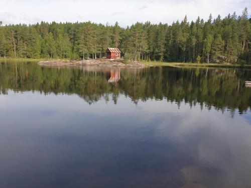 a large lake with a cabin in the middle of it at Guesthouse Nature Trails Sweden in Övre Älgestad