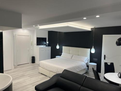 a bedroom with a white bed and a couch at Black and White Suite Castro Urdiales in Castro-Urdiales