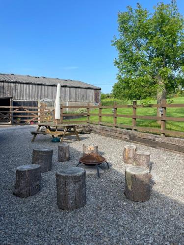 a picnic table and some logs and a table and a fence at Rivington Barn in Kerne Bridge