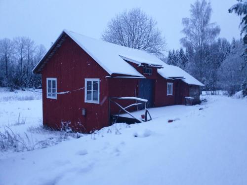 a red barn covered in snow in a field at Guesthouse Nature Trails Sweden in Övre Älgestad