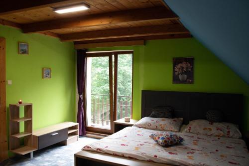1 dormitorio con paredes verdes y 1 cama con ventana en Chata Vikinka - dovolená v přírodě, 