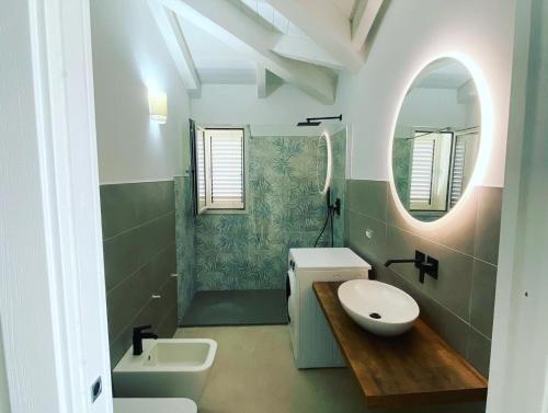 een badkamer met een wastafel, een toilet en een spiegel bij Villa Lorisa in Tanaunella