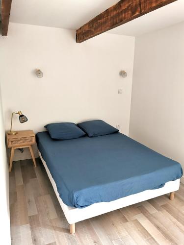 een slaapkamer met een bed met blauwe lakens en een tafel bij Charmante maison de village in Caumont-sur-Durance