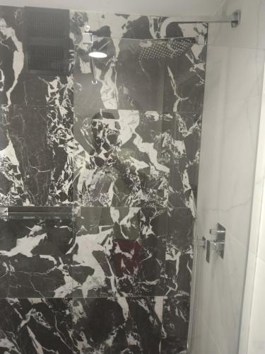 a bathroom with a black and white marble shower at Apartment Wroblewskiego in Ustka