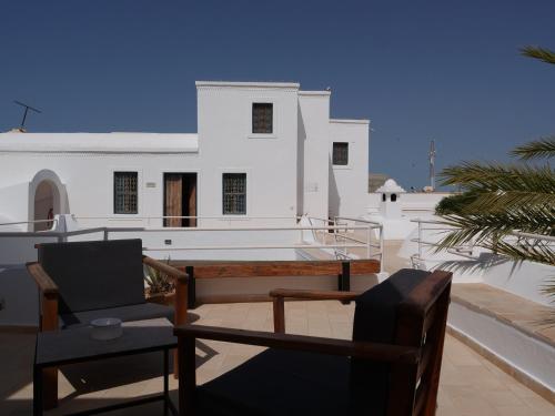 a balcony with chairs and a building in the background at Dar Ennour Djerbahood Erriadh in Houmt Souk