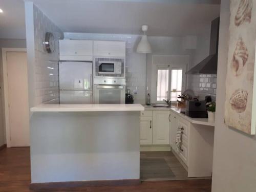 eine Küche mit weißen Schränken und einer weißen Arbeitsplatte in der Unterkunft Apartamento en Cádiz playa Victoria in Cádiz
