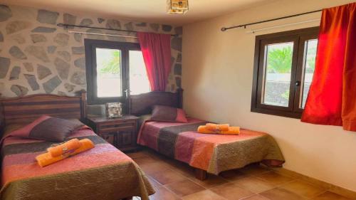 a bedroom with two beds and two windows at Preciosa Casa Cristian y María con piscina privada in Tías