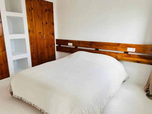een slaapkamer met een wit bed en een houten hoofdeinde bij LeS OiSeauX in Nazaret