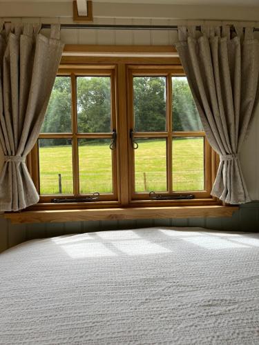 a bedroom with a bed and a window at Troytown Farm Shepherds hut in Puddletown