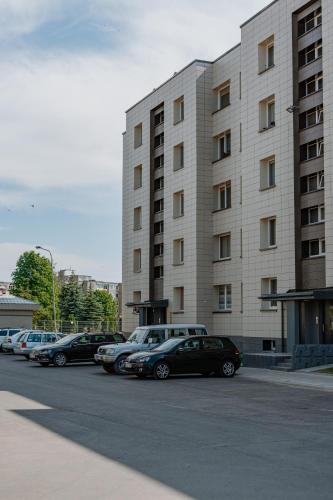 a parking lot with cars parked in front of a building at BALI apartment in central Mažeikiai SELF CHECK-IN 24H in Mažeikiai
