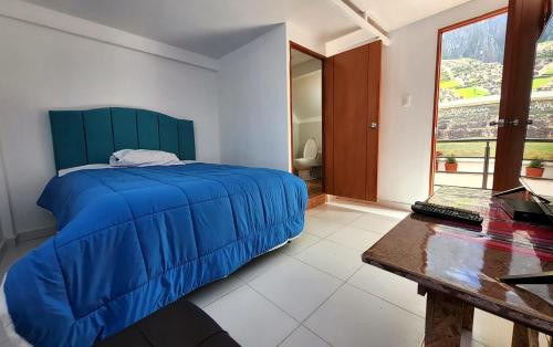 a bedroom with a blue bed and a table at Peru Hostel Inn Plaza in Cusco