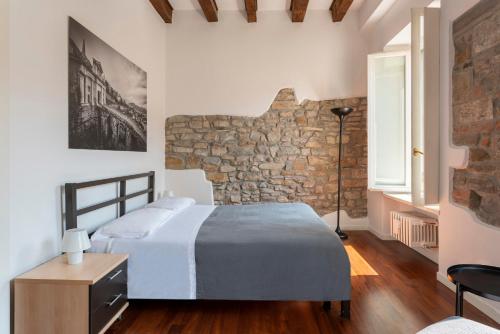1 dormitorio con cama y pared de piedra en Casa di Sofia Città Alta, en Bérgamo