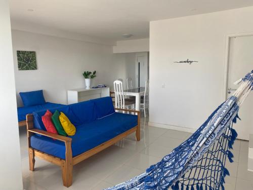 a living room with a blue couch and a hammock at Apt agradabilíssimo vista mar in Lauro de Freitas