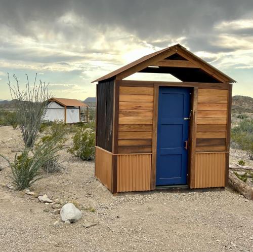 un pequeño cobertizo con una puerta azul en el desierto en Rancho de los Arboles Muertos en Terlingua