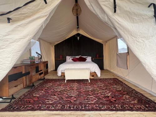a bedroom in a tent with a bed and a rug at Rancho de los Arboles Muertos in Terlingua