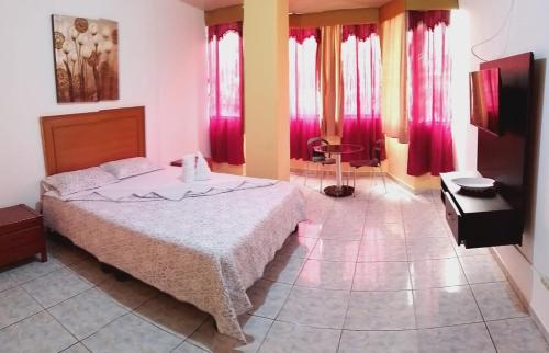 Olmedo Plaza Hotel في غواياكيل: غرفة نوم بسرير كبير مع ستائر حمراء