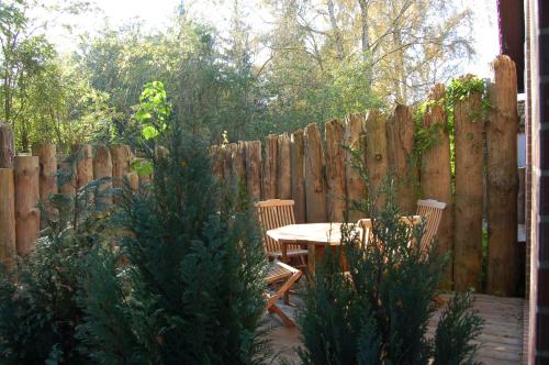 eine Terrasse mit einem Tisch, Stühlen und einem Zaun in der Unterkunft Ferienhaus im urigen Garten bzw Eulenhaus in Zingst