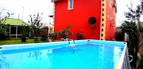 a swimming pool in front of a red building at Villa ELO in Kebele in Gabala