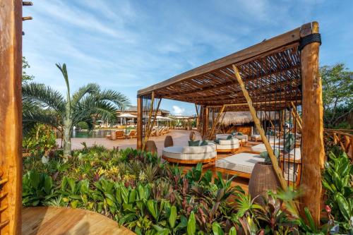 a resort with a pavilion with chairs and palm trees at Hotel Shibari - Restaurant & Cenote Club in Tulum