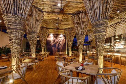 a restaurant with wooden tables and chairs and ceilings at Hotel Shibari - Restaurant & Cenote Club in Tulum