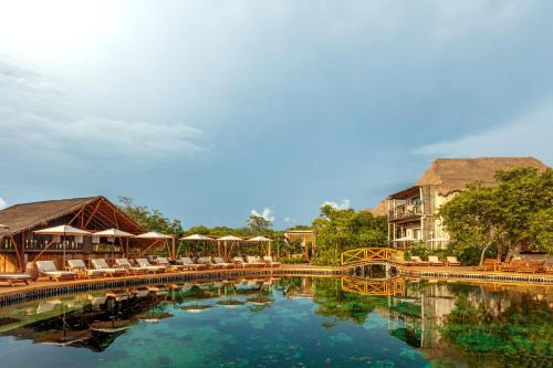 a pool at a resort with chairs and a building at Hotel Shibari - Restaurant & Cenote Club in Tulum