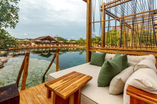 a living room with a couch next to a body of water at Hotel Shibari - Restaurant & Cenote Club in Tulum