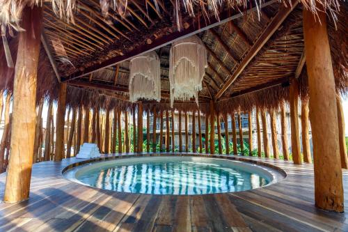 a swimming pool in a bamboo building with a ceiling at Hotel Shibari - Restaurant & Cenote Club in Tulum