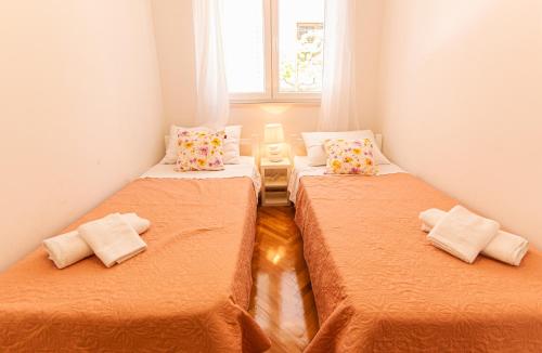 two beds in a small room with orange sheets at Stylish apt Marta, private parking,BBQ in Stobreč in Stobreč