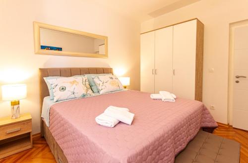a bedroom with a pink bed with towels on it at Stylish apt Marta, private parking,BBQ in Stobreč in Stobreč