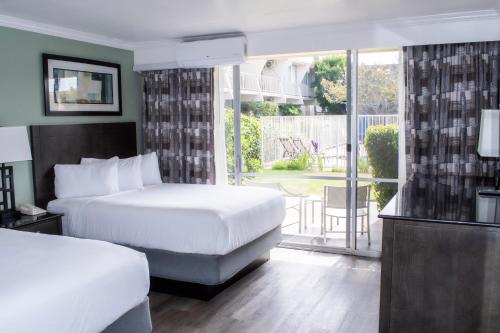 a hotel room with two beds and a balcony at Travelodge by Wyndham Monterey Bay in Monterey