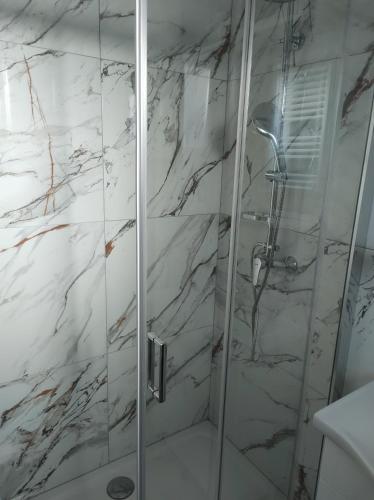 a bathroom with a shower with white marble walls at Happy room in Karlovac
