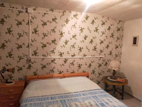 1 dormitorio con 1 cama y flores en la pared en Monolocali Tra Rieti e Terminillo tra le nevi, en Terminillo
