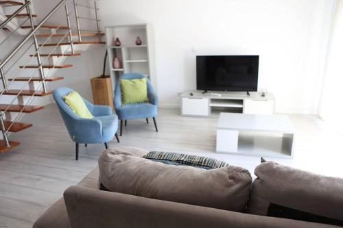 un soggiorno con divano, sedie e TV di Lisbon Tagus River - Almada ad Almada