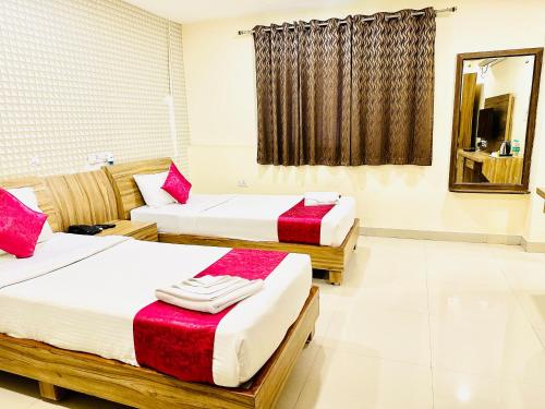 two beds in a room with red and white sheets at The Landmark Banjara Hills - Hyderabad in Hyderabad