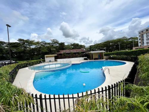 een groot blauw zwembad met een hek eromheen bij Espectacular apartamento Conjunto Piedemonte in Villavicencio