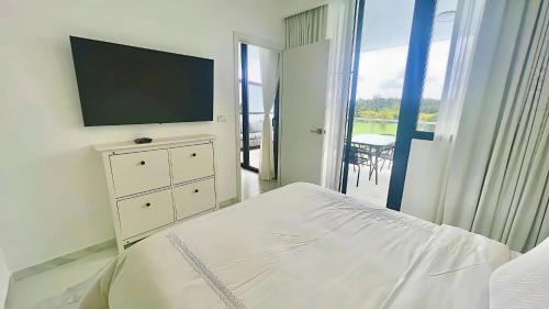 a bedroom with a bed with a television and a balcony at Cana Rock Star Pool View Whith BBQ in Punta Cana