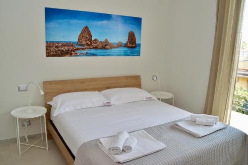 Un dormitorio con una cama blanca con toallas. en Home 13 en San Gregorio di Catania