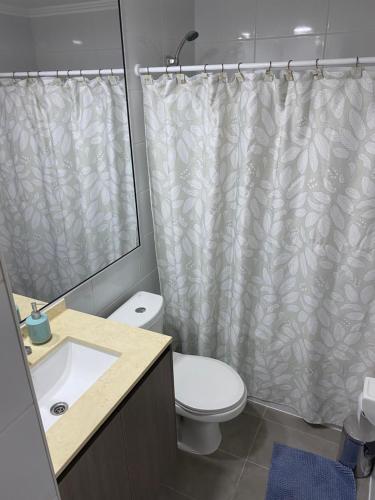 y baño con aseo y cortina de ducha. en Edificio Lynch Iquique, en Iquique