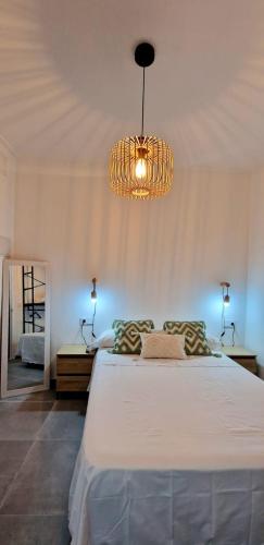 a bedroom with a large white bed with a chandelier at Loft el Baix - Cullera in Cullera