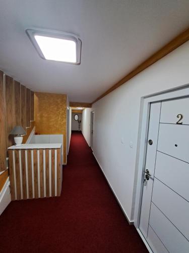 an empty hallway with a red carpet and a door at In apartman in Nikšić