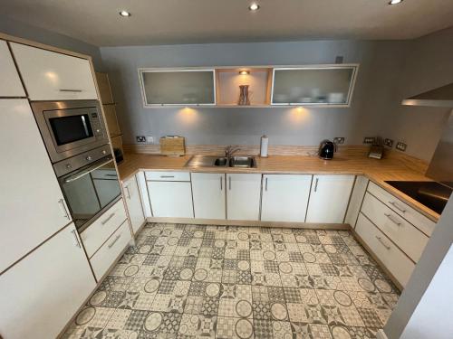 mit Blick auf eine Küche mit weißen Schränken in der Unterkunft Corinthian Quay Apartment in Edinburgh