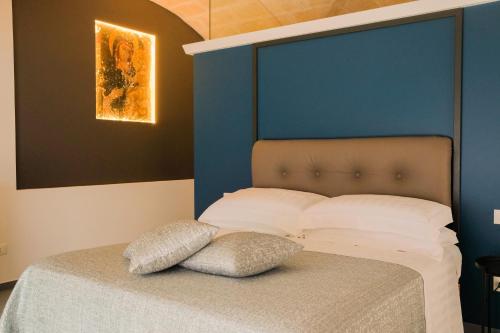 un letto con testiera blu e due cuscini sopra di Suite Polignani by STHEY a Monopoli